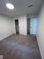 Room featuring gray carpet flooring, white walls, and a round ceiling light fixture - 