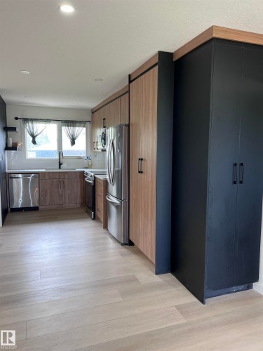 Contemporary kitchen featuring wood-finish flooring, recessed lighting, and a stainless steel appliance suite - 11911 133 Avenue, Edmonton, AB 