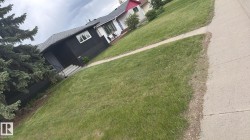 Front yard with established evergreen landscaping, concrete walkway, and paved sidewalk - 