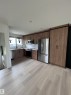 Contemporary kitchen featuring wood-finish cabinetry, stainless steel appliances, white subway tile backsplash, and light wood-finish flooring - 11911 133 Avenue, Edmonton, AB 