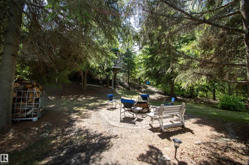 Outdoor living space featuring a gravel patio, a metal fire pit, and a surrounding wooded landscape - 104 60201 Rng Rd 122, Rural St. Paul County, AB 