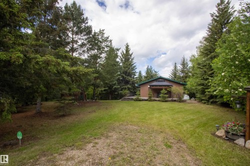 Lush green lawn surrounding a brown-sided house with a dark green roof - 104 60201 Rng Rd 122, Rural St. Paul County, AB 