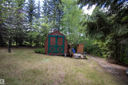Expansive treed lot featuring a red and green storage shed, gravel pathway, and additional smaller shed - 104 60201 Rng Rd 122, Rural St. Paul County, AB 