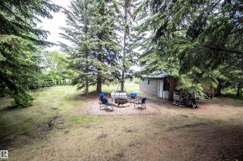 Exterior building with wood siding and a metal roof, surrounded by mature evergreen trees - 104 60201 Rng Rd 122, Rural St. Paul County, AB 