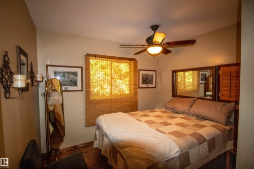 Interior room featuring wood-finish flooring, a window with bamboo shades, and a ceiling fan with integrated lighting - 104 60201 Rng Rd 122, Rural St. Paul County, AB 