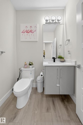 Modern powder room featuring wood-finish flooring, a contemporary floating vanity with a white countertop and rectangular undermount sink, and a sleek wall-mounted faucet - 449 Roberts Cres, Leduc, AB 
