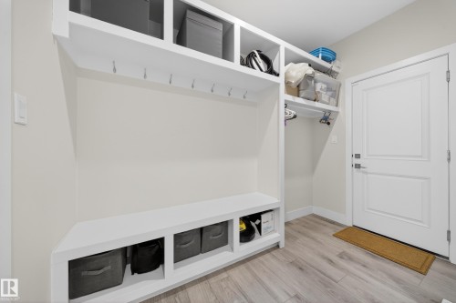 Built-in white mudroom storage system featuring a bench, open shelving, and integrated coat hooks - 449 Roberts Cres, Leduc, AB 