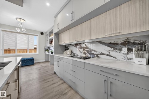 Contemporary kitchen featuring light wood-finish flooring, white countertops, and a striking black and white patterned backsplash - 449 Roberts Cres, Leduc, AB 