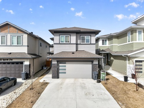 Contemporary two-story residence featuring a gray and light gray siding exterior, dark trim accents, and a front-facing garage with horizontal frosted glass inserts - 449 Roberts Cres, Leduc, AB 