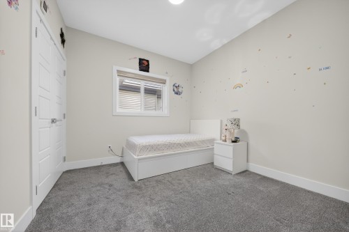 Light-filled room featuring a paneled interior door, a large window with horizontal blinds, plush grey carpeting, and white baseboards - 449 Roberts Cres, Leduc, AB 