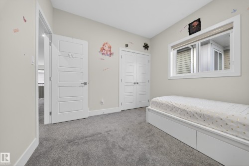 Neutral tone wall paint, gray carpeting, a double-panel interior door, a bi-fold closet door, and a white framed window - 449 Roberts Cres, Leduc, AB 