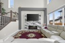 Living area with a two-story ceiling, featuring a modern fireplace surround with a stone-look finish and an inset electric fireplace - 449 Roberts Cres, Leduc, AB 