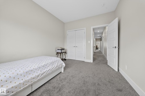 Carpeted room with double-door closet featuring modern panel doors and neutral wall finishes - 449 Roberts Cres, Leduc, AB 