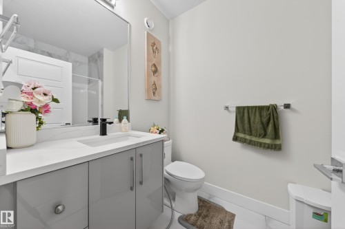 Modern bathroom featuring a single vanity with gray cabinetry, a white countertop, and a rectangular undermount sink with a matte black faucet - 449 Roberts Cres, Leduc, AB 