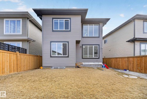 Contemporary two-story exterior featuring gray siding, dark trim accents, multiple windows, and a wood privacy fence - 449 Roberts Cres, Leduc, AB 