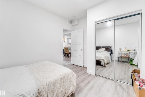 Bedroom featuring wood-finish flooring, white walls, and a mirrored closet with sliding doors - 449 Roberts Cres, Leduc, AB 