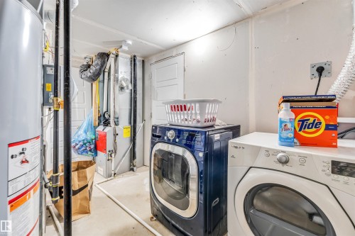 Dedicated laundry area featuring a water heater, furnace, and a utility door - 449 Roberts Cres, Leduc, AB 