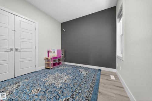 Room featuring wood-finish flooring, a contemporary window, and a dark accent wall - 449 Roberts Cres, Leduc, AB 