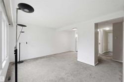 Spacious room featuring light gray carpeting, neutral wall finishes, and abundant natural light from multiple windows - 