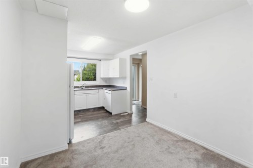 Kitchen area with white cabinetry, dark countertops, and a window above the sink - 17325 85 Avenue Nw, Edmonton, AB 