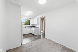 Kitchen area with white cabinetry, dark countertops, and a window above the sink - 