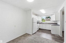 Kitchen area featuring white cabinetry, a single basin sink, and dark countertops - 