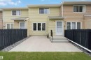 Rear exterior featuring a concrete patio, black wood fence, and a grass lawn - 17325 85 Avenue Nw, Edmonton, AB 
