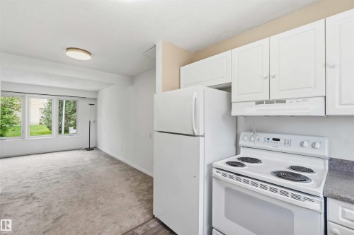 Kitchenette area featuring white cabinetry, a white refrigerator, and an electric range with an overhead exhaust fan - 17325 85 Avenue Nw, Edmonton, AB 