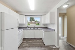 Kitchen featuring white cabinetry, dark countertops, wood-finish flooring, and white appliances - 