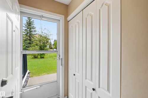 Entryway featuring a storm door, white panel door, and white bi-fold closet doors with black hardware - 17325 85 Avenue Nw, Edmonton, AB 