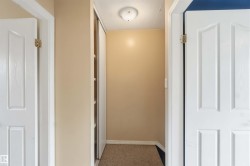 Hallway featuring neutral-toned walls, white trim, and textured carpeting - 