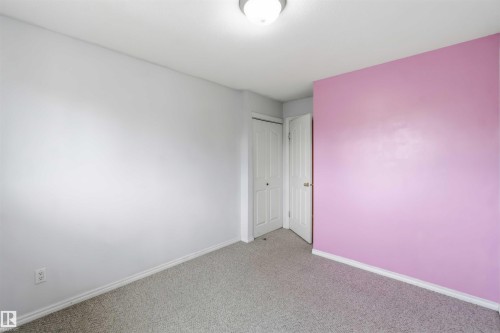 Interior room featuring light gray walls, a single pink accent wall, and a gray carpeted floor - 17325 85 Avenue Nw, Edmonton, AB 