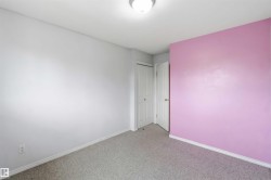 Interior room featuring light gray walls, a single pink accent wall, and a gray carpeted floor - 