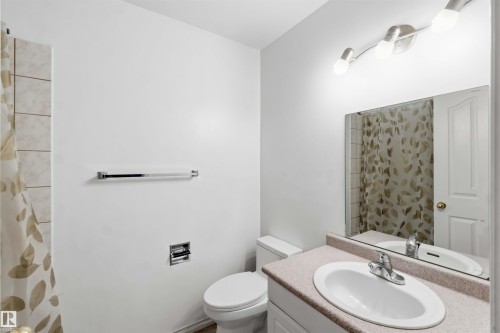 Bathroom featuring a white toilet, chrome towel bar, and a vanity with an integrated sink and laminate countertop - 17325 85 Avenue Nw, Edmonton, AB 