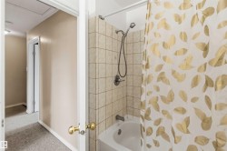 Bathroom featuring a white tub, light-toned square tile surround, and a brushed nickel shower fixture - 