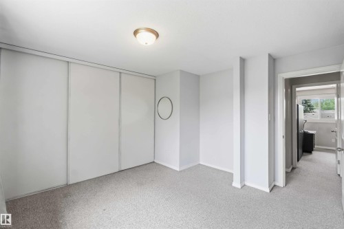 Carpeted room with a ceiling-mounted light fixture and sliding closet doors - 17325 85 Avenue Nw, Edmonton, AB 