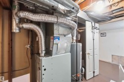 Utility room featuring a water heater, furnace, and exposed ceiling joists - 