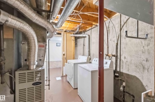 Utility area featuring a Carrier furnace, exposed ductwork, concrete walls, and a laundry station with a washer and dryer - 17325 85 Avenue Nw, Edmonton, AB 