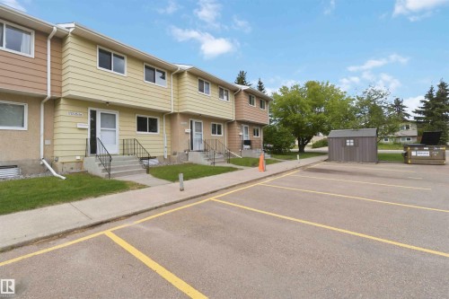 Townhouse exterior featuring a two-story design with siding and stucco finishes, individual front entrances with concrete steps and metal railings, and a manicured lawn - 17325 85 Avenue Nw, Edmonton, AB 