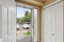 Entryway featuring a white paneled door, storm door, frosted glass sidelight, and a double-door closet with black hardware - 17325 85 Avenue Nw, Edmonton, AB 