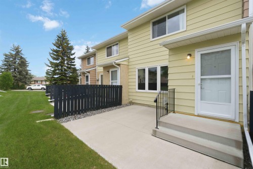 Private patio area with concrete slab, black picket fencing, and surrounding green space - 17325 85 Avenue Nw, Edmonton, AB 