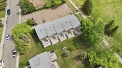 Multi-unit residential structure featuring individual patios and a light-colored shingle roof - 