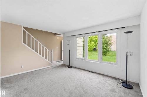 Living area featuring a three-panel window overlooking green landscaping - 17325 85 Avenue Nw, Edmonton, AB 