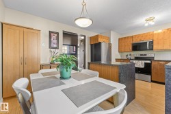 Eat-in kitchen featuring wood-finish cabinetry, stainless steel appliances, dark stone-finish countertops, and wood-finish flooring - 