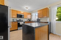 Kitchen featuring wood-finish cabinetry, dark countertops, a central island, and wood-finish flooring - 