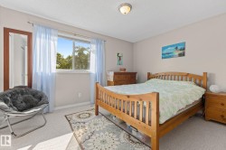 Bedroom featuring a window with natural light, light-toned carpeting, neutral wall paint, a ceiling-mounted light fixture, and a full-length mirror - 