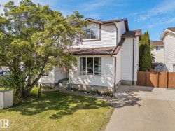 White siding exterior with brown trim accents, featuring multiple windows - 