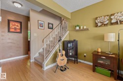 Wood-finish flooring throughout, complemented by a carpeted staircase with decorative white railings - 