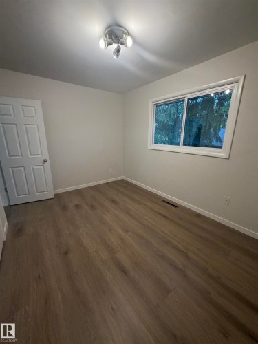 Room featuring light wood-finish flooring, white baseboards, a white paneled door, and a white window frame - 9640 74 Avenue, Edmonton, AB 