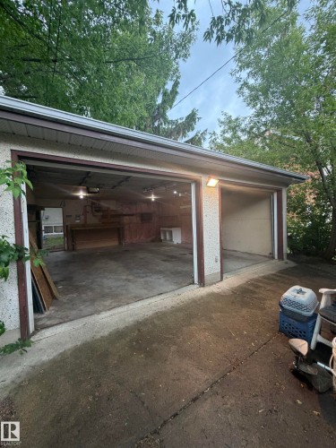 Two-car garage featuring concrete flooring, interior lighting, and an exterior wall-mounted light fixture - 9640 74 Avenue, Edmonton, AB 